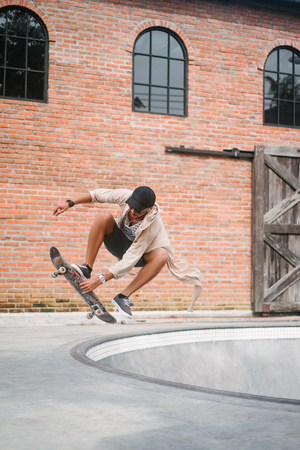 handsome skater jumping out of pool in skateparkの写真素材