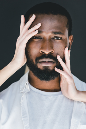 cropped image of girlfriend touching african american boyfriend face isolated on blackの写真素材