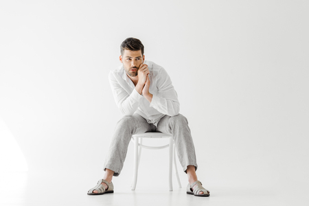 handsome man in linen clothes sitting on chair  isolated on grey backgroundの写真素材