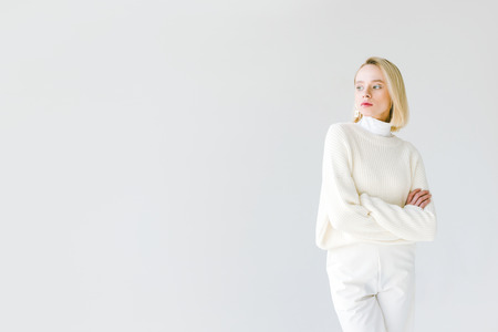 beautiful stylish blonde woman in white clothes standing with crossed arms isolated on whiteの写真素材