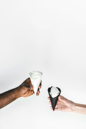 cropped image of multicultural couple holding ice cream cones isolated on whiteの写真素材