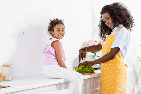 african american man and daughter cutting lettuce on kitchenの写真素材
