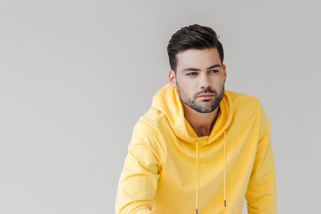 handsome young man in yellow hoodie looking away isolated on whiteの写真素材