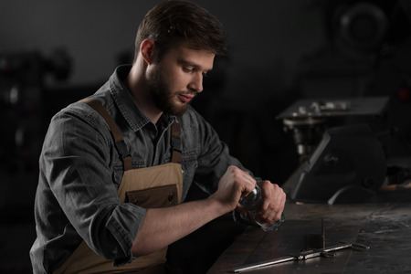young male worker opening bottle of water and sitting at table