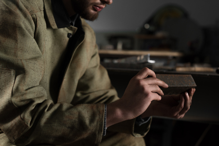 cropped image of young male worker holding and looking at metal part at factoryの写真素材