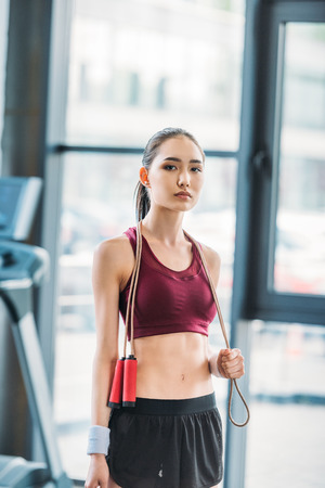 portrait of young asian sportswoman with skipping rope at gymの写真素材