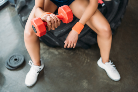 cropped image of sportswoman in wristbands doing exercise with dumbbell at gymの写真素材