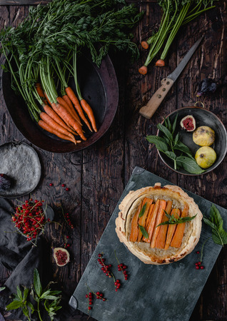 elevated view of tasty pie with carrots, figs and currants on wooden tableの写真素材