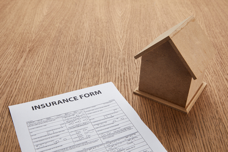 close-up view of insurance form and small house model on wooden table with copy spaceの写真素材