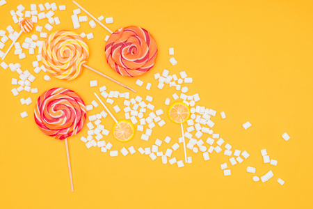 top view of scattered marshmallows and lollipops isolated on orangeの写真素材