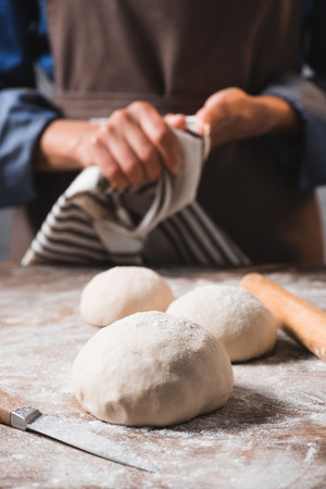 selective focus of raw dough for pizza on surface and woman with linenの写真素材