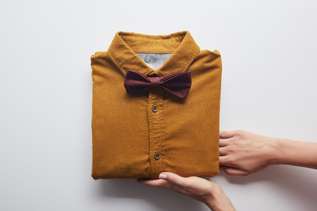 cropped image of woman holding brown shirt and bow tie on whiteの写真素材