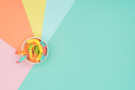 top view of jelly candies in paper container on colored surfaceの写真素材