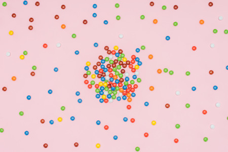 elevated view of scattered yummy dragee candies isolated on pinkの写真素材