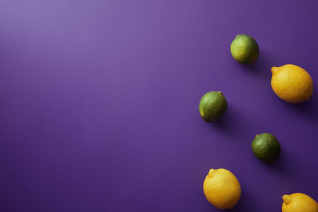 top view of limes and lemons on violet surfaceの写真素材
