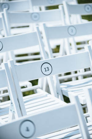 close-up view of empty white chairs with numbers on green lawnの写真素材
