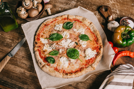 top view of italian pizza, ingredients and knife on wooden tabletopの写真素材