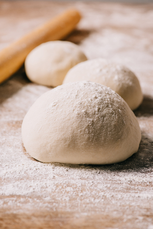 selective focus of raw dough for pizza and rolling pin on tabletopの写真素材