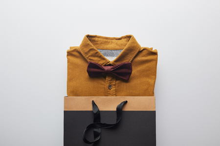 top view of new brown shirt and bow tie in shopping bag isolated on whiteの写真素材
