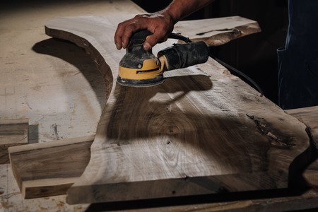 partial view of carpenter working with electric plane at workshopの写真素材