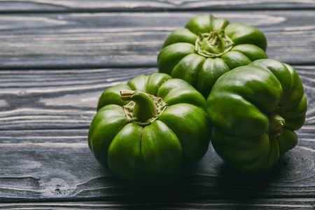 Bunch of green bell peppers on dark wooden tableの写真素材