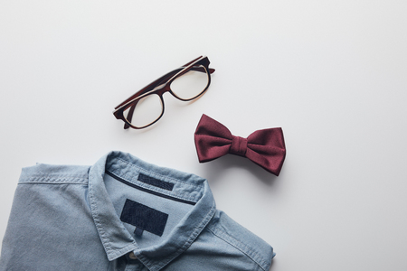 top view of blue shirt, burgundy bow tie and glasses isolated on whiteの写真素材