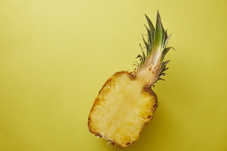 top view of half of pineapple on yellow surfaceの写真素材