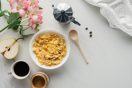top view of bowl of dry cereal with coffee and alstroemeria bouquet on whiteの写真素材