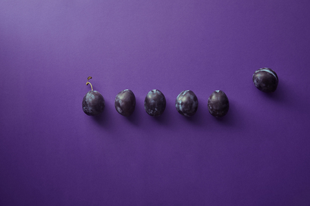 top view of ripe plums on violet surfaceの写真素材