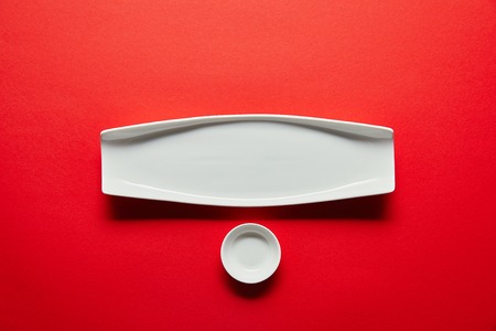 top view of empty white plate and bowl for sushi on red backgroundの写真素材