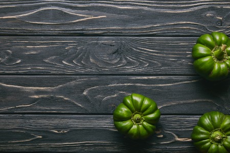 Green bell peppers on dark wooden table