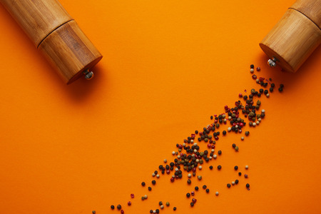 top view of spice containers and peppercorns on orange backgroundの写真素材