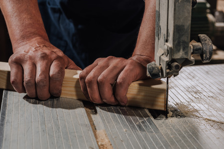 partial view of woodworker using electric drill on wood at workshopの写真素材