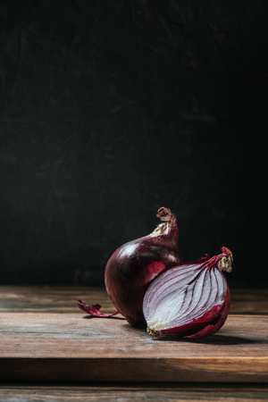 ripe cut red onion on cutting board isolated on blackの写真素材