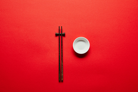 top view of arranged chopsticks and empty bowl on red backdropの写真素材