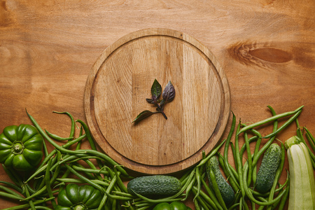 Organic raw green vegetables with round board on wooden tableの写真素材