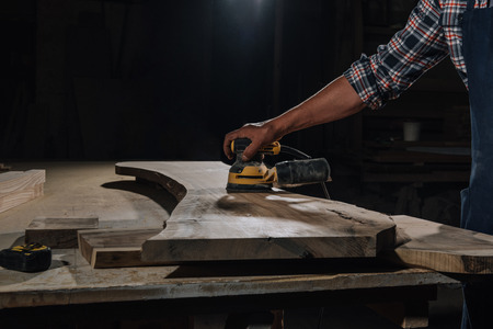 partial view of carpenter working with electric plane at workshopの写真素材