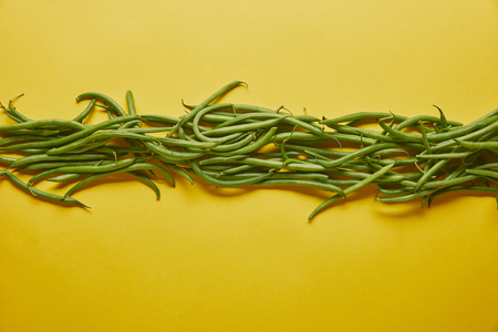 Green beans in a row on yellow backgroundの写真素材