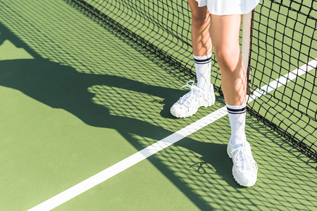 partial view of female tennis player standing near tennis net on courtの写真素材