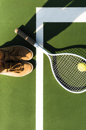 partial view of female tennis player standing near tennis racket and ball on courtの写真素材