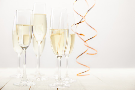 close up view of champagne glasses with ribbons on white wooden table, holiday conceptの写真素材