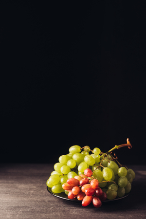 close-up view of fresh ripe juicy grapes on wooden table on blackの写真素材