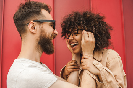 happy young interracial couple in eyeglasses having fun together on streetの写真素材