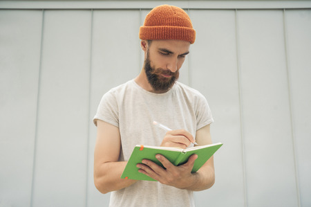 handsome young bearded man taking notes in notepadの写真素材