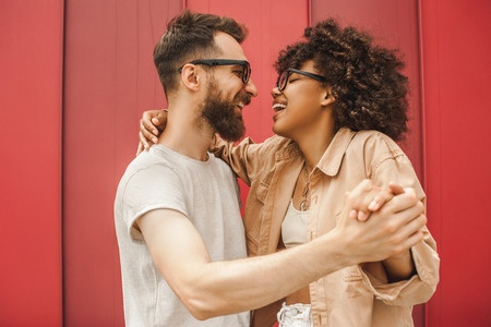 side view of happy young multiethnic couple dancing and holding handsの写真素材