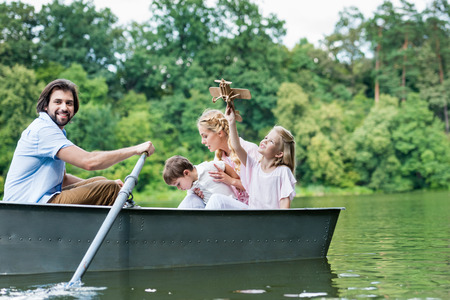 happy young family riding boat on lake at park togetherの写真素材