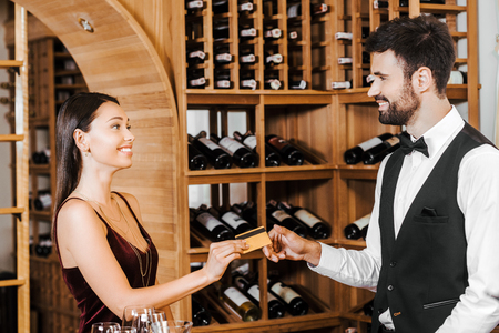wine steward taking credit card from female customer at wine storeの写真素材