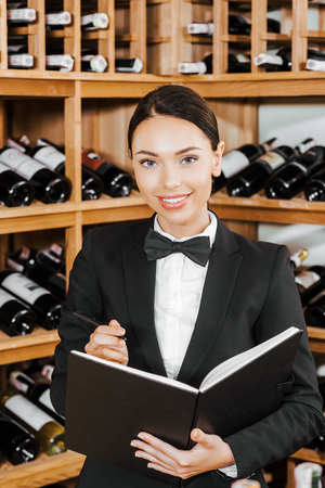 beautiful female wine steward with notebook at wine storeの写真素材