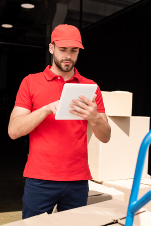 portrait of delivery man in red uniform using digital tabletの写真素材