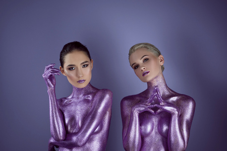 attractive multicultural girls in purple glitter posing for fashion shoot, isolated on violetの写真素材